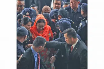 TEPI, BERI LALUAN: Datin Seri Rosmah (berbaju warna jingga) tiba di mahkamah pagi semalam di mana beliau dikenakan 12 pertuduhan pengubahan wang haram berjumlah lebih RM7 juta ($2.3 juta) selain pertuduhan gagal mengemukakan penyata pendapatan kepada Lembaga Hasil Dalam Negeri. - Foto AFP
