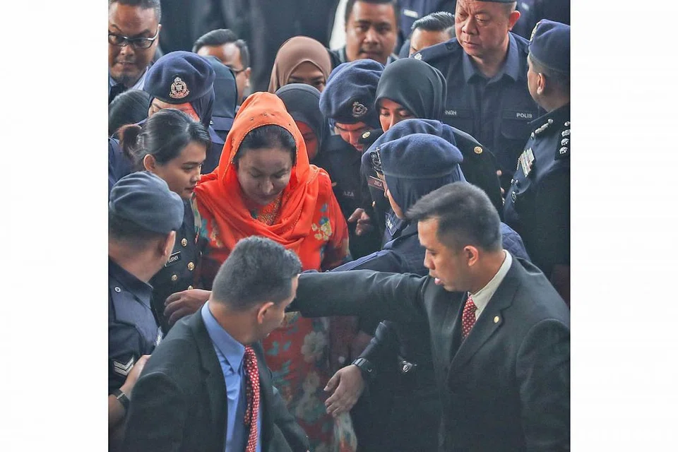 TEPI, BERI LALUAN: Datin Seri Rosmah (berbaju warna jingga) tiba di mahkamah pagi semalam di mana beliau dikenakan 12 pertuduhan pengubahan wang haram berjumlah lebih RM7 juta ($2.3 juta) selain pertuduhan gagal mengemukakan penyata pendapatan kepada Lembaga Hasil Dalam Negeri. - Foto AFP