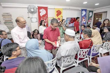 TERIMA SUMBANGAN: Menteri Negara Kanan (Undang-Undang dan Kesihatan), Encik Edwin Tong, mengagihkan sumbangan wang tunai kepada penerima bantuan sambil diperhatikan oleh presiden MKAC, Encik Ameerali Abdeali (kiri). - Foto BH oleh IQBAL FAIZAL