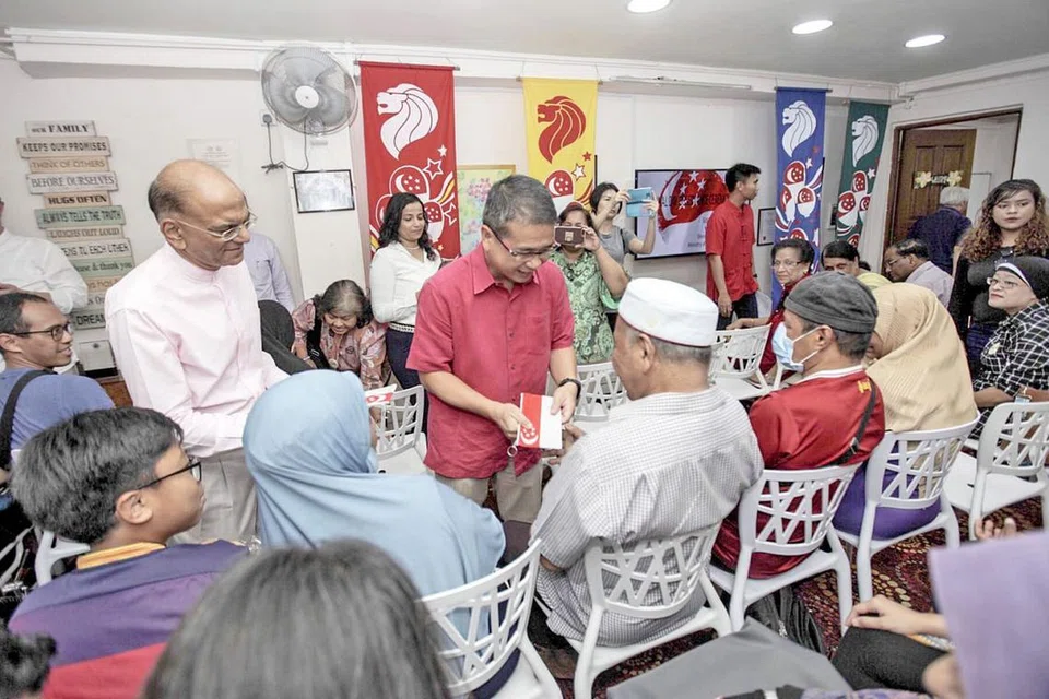 TERIMA SUMBANGAN: Menteri Negara Kanan (Undang-Undang dan Kesihatan), Encik Edwin Tong, mengagihkan sumbangan wang tunai kepada penerima bantuan sambil diperhatikan oleh presiden MKAC, Encik Ameerali Abdeali (kiri). - Foto BH oleh IQBAL FAIZAL