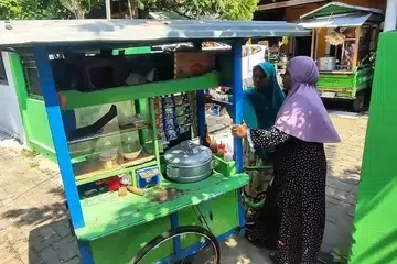 Cik Mislicha (kiri) bersama anak perempuannya menolak kereta sorong menjual makanan ringan yang menjadi sumber rezekinya di Pasuruan, Jawa Timur, Indonesia pada 18 April, usaha kecil yang akhirnya membolehkan beliau menunaikan haji selepas puluhan tahun menabung.