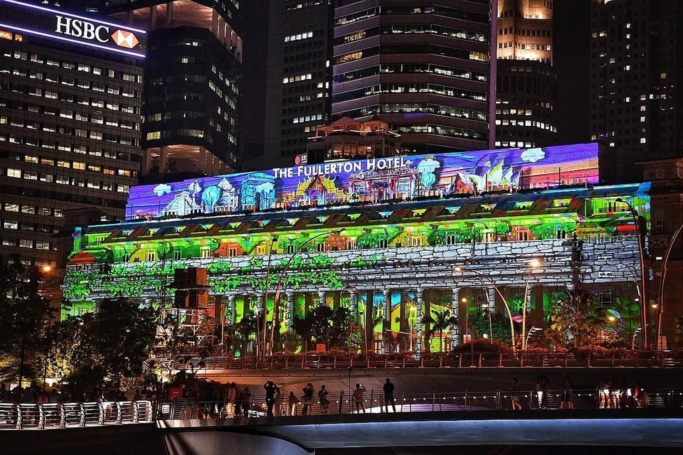 Sementara gambar kanan bawah pula ialah karya seni yang dihasilkan beberapa pelajar dan penerima bantuan persatuan kebajikan yang bakal dipaparkan melalui pancaran cahaya pada permukaan bangunan seperti Hotel The Fullerton Singapore dan The Merlion. - Foto COLOSSAL