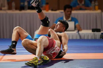 TARUH DI GELANGGANG: Aryan Azman (berbaju biru) bergusti dengan atlet dari Kemboja semasa perlawanan peringkat awal. - Foto SPORT SINGAPORE
