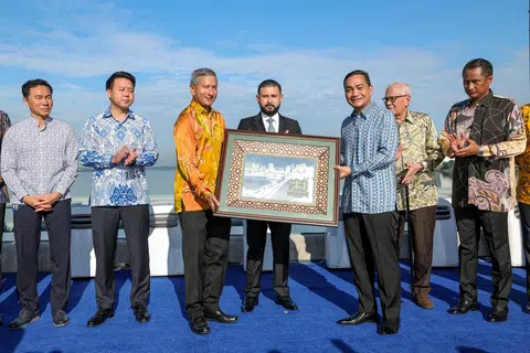 Pemangku Sultan Johor Tunku Mahkota Ismail (tengah) berkenan menyaksikan penyerahan cenderahati daripada Menteri Besar Johor Datuk Onn Hafiz Ghazi (tiga dari kanan) kepada Menteri Ehwal Luar Singapura, Dr Vivian Balakrishnan (tiga dari kiri) pada Sambutan 100 Tahun Tambak Johor di tengah tambak sempadan Johor dan Singapura pada 28 Jun.