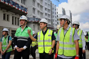 Menteri Negara Kanan (Tenaga Manusia merangkap Pertahanan), Encik Zaqy Mohamad (tengah), dan Menteri Negara Kanan (Perhubungan dan Penerangan merangkap Pembangunan Negara), Encik Tan Kiat How (depan, kanan), mengunjungi  tapak binaan flat Lembaga Perumahan dan Pembangunan (HDB) baru di Hougang Avenue 3 pada 2 Februari. Bersama mereka adalah pengerusi eksekutif syarikat pembinaan, Expand Construction Pte Ltd, Encik Von Lee (kiri).