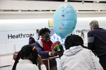 Seorang wanita dilihat memegang sejambak bunga dan belon di Terminal 2 Lapangan Terbang Antarabangsa Heathrow, sehari selepas kebakaran di sebuah pencawang elektrik berhampiran menyebabkan gangguan bekalan kuasa di lapangan terbang itu, berhampiran London, Britain, pada 22 Mac 2025.