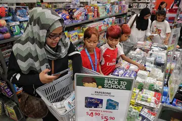 HULURKAN BANTUAN: Pengasas Project Goodwill Aid, Cik Siti Nurani Mohd Salim (kiri), dan sukarelawan Cik Sufiyyah Ithnin (dua dari kanan), membeli peralatan sekolah bagi pelajar dari keluarga memerlukan. (dari kiri) Puteri Nurinsyirah Abdullah, 11 tahun; Muhammad Syaffiq Yusri, 10 tahun; Muhammad Sofiyan Shah Yusri, lapan tahun; dan Rabeeatul Adawiyah Edros, sembilan tahun di Tiong Bahru Plaza. - Foto BH oleh KEVIN LIM