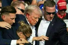 Calon presiden Republikan, Encik Donald Trump (tengah), yang ditembak semasa satu acara kempen, segera dibawa turun dari pentas oleh Perkhidmatan Risik Amerika Syarikat di Pennsylvania.  