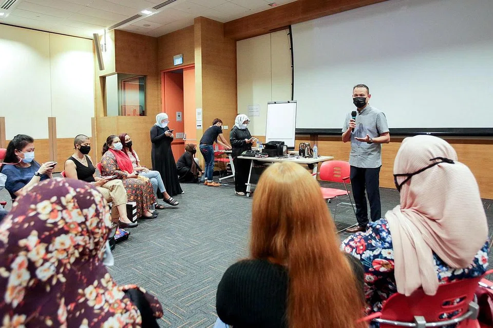BERSAMA PEKERJA: Encik Fahmi bersama peserta program Wanita Kembali Bekerja (BWW) di Pameran Pekerjaan dan Kemahiran yang dianjurkan bersama Institut Pembelajaran Sepanjang Hayat (LLI), Mendaki dan NTUC pada bulan lalu. - Foto YAYASAN MENDAKI