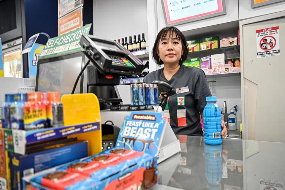 Seorang jurujual yang bertugas di kedai runcit, 7-Eleven mengurus kaunter wang dan memberi perkhidmatan pelanggan yang cekap dan mesra.
