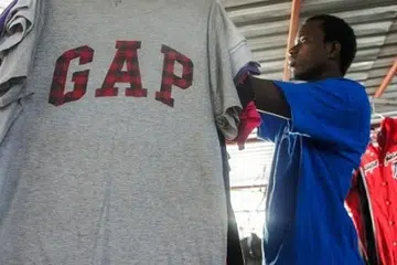 NIAGA BAJU TERPAKAI: Encik Mamadou Sarr menyiapkan gerai bajunya di Pasar Colobane, kawasan perdagangan terbesar bagi perniagaan baju terpakai di Dakar, Senegal. - Foto AFP