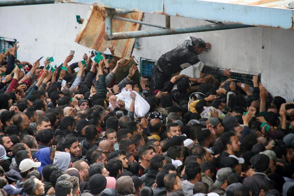 Para penduduk berkumpul beramai-ramai bagi mendapatkan bantuan di gudang Agensi Bantuan dan Kerja Menyelamat Pertubuhan Bangsa-Bangsa Bersatu (PBB) bagi pelarian Palestin (UNRWA) di Gaza.