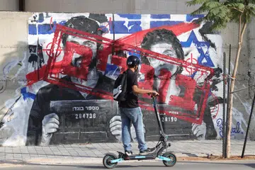 Seorang penunggang skuter melintasi grafiti yang memaparkan pengarah filem Israel, Encik Yuval Abraham (kiri) dan Cik Rachel Szor, bersama perkataan ‘pengkhianat’ dalam bahasa Ibrani di Ashdod, Israel, pada 15 September 2026. Kedua-duanya memenangi Hadiah Khas Juri di Festival Filem Venice menerusi dokumentari ‘NAZA’ mengenai kematian orang awam di Gaza, yang mencetuskan kontroversi politik dan kecaman di Israel serta ancaman terhadap pembikin filem dan keluarga mereka. – Foto EPA
