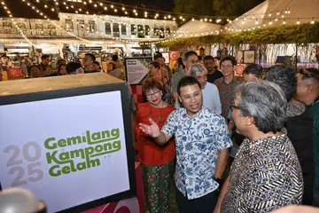 Menteri Pembangunan Negara, Encik Desmond Lee, berinteraksi dengan  pengerusi One Kampong Gelam, Encik Zaki Ma’arof, di majlis pembukaan rasmi bazar Ramadan Kampong Gelam 2025. Bersama mereka ialah Anggota Parlimen GRC Jalan Besar, Cik Denise Phua (baju oren).