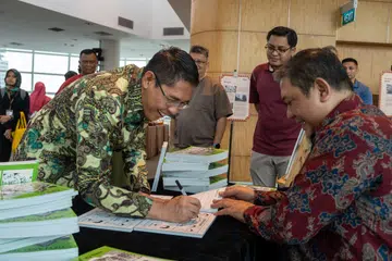Menteri di Pejabat Perdana Menteri yang juga Menteri Kedua (Ehwal Luar merangkap Pendidikan), Dr Mohamad Maliki Osman menandatangani buku komik lukisan kartunis Encik Kasim Bachik.