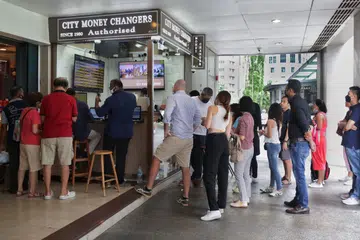 BERATUR TUKAR WANG: Ramai orang beratur di gerai pengurup Citi Money Changers di The Arcade untuk menukar wang asing, termasuk ringgit yang turun ke paras rendah berbanding dolar Singapura.