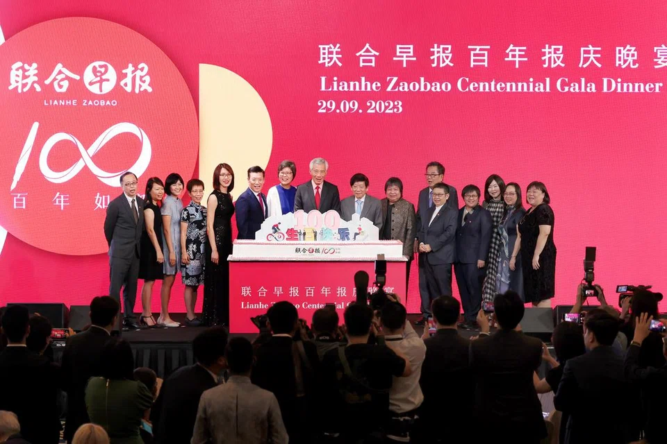 SAMBUTAN SEABAD: Perdana Menteri Lee Hsien Loong  (bertali leher merah) diapit Ketua Editor Kumpulan Media Cina SMT, Cik Lee Huay Leng (kanannya), dan Pengerusi SMT, Encik Khaw Boon Wan (kirinya), Editor Lianhe Zaobao ,Encik Goh Sin Teck (enam dari kiri), dan Ketua Pegawai Eksekutif SMT, Cik Teo Lay Lim (sebelah Encik Khaw),  bergambar sama di sambutan 100 tahun Zaobao pada Jumaat.