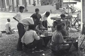 Sekumpulan pemuda menjamu selera dengan sate yang dibeli daripada pegerai jalanan pada 1 Syawal. Gambar ini diambil Mac 1962.