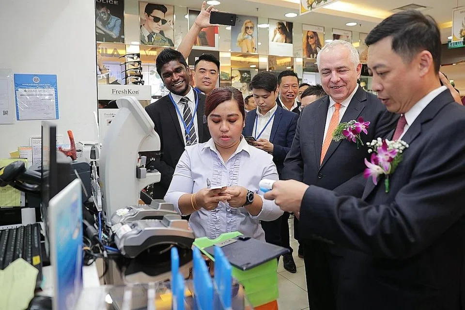 LEBIH MUDAH: Encik Jeffrey Goh (kanan) yang ditemani CEO Kumpulan PayNet, Encik Peter Schiesser (dua dari kanan), membuat bayaran menggunakan khidmat rentas sempadan di salah sebuah kedai semasa pelancaran Nets-PayNet di City Square di Johor Baru. - Foto BH oleh GIN TAY