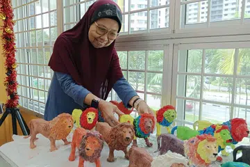 Cik Rubiah Rahim melibatkan diri dalam pelbagai kegiatan seperti senaman pagi, permainan Bingo serta seni dan kraf di Pusat Penuaan Aktif (AAC) Lions Befrienders @ 420A Clementi.