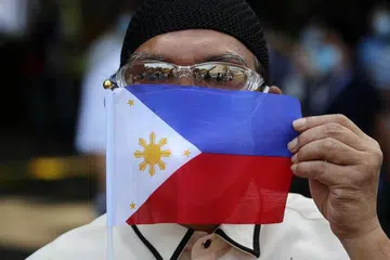 LANGKAH MENGURANGI KEPADATAN PENDUDUK: Presiden Filipina, Encik Rodrigo Duterte, menawarkan wang tunai dan ganjaran lain, untuk penduduk berhijrah keluar dari Manila demi mengurangi kepadatan penduduk kota itu. Kelihatan seorang kakitangan awam memaparkan bendera Filipina semasa penularan koronavirus di sebuah kawasan setinggan di Manila, Filipina, pada 28 Mei lalu. 