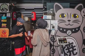 TEGAS IKUT PERATURAN: Kakitangan di Wakuwaku Yakiniku hanya akan membenarkan pelanggan masuk jika aplikasi TraceTogether mereka menyatakan bahawa mereka sudah divaksin sepenuhnya. - Foto oleh NUR DIYANA TAHA