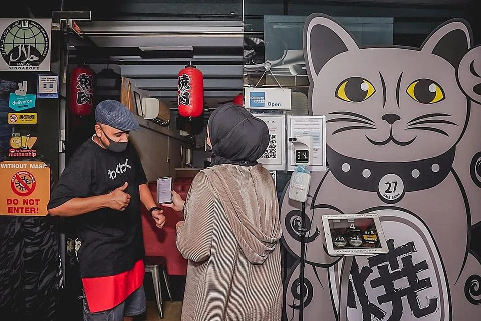 TEGAS IKUT PERATURAN: Kakitangan di Wakuwaku Yakiniku hanya akan membenarkan pelanggan masuk jika aplikasi TraceTogether mereka menyatakan bahawa mereka sudah divaksin sepenuhnya. - Foto oleh NUR DIYANA TAHA