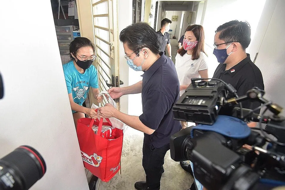 TAWAR BANTUAN: (Dua dari kiri) Menteri Pendidikan, Encik Lawrence Wong menyampaikan habuan kepada penerima sambil disaksikan oleh Encik Alex Yam, Mayor CDC North West (kanan); dan Cik Hany Soh, Penasihat Pertubuhan Akar Umbi Woodgrove. - Foto CDC NORTH WEST