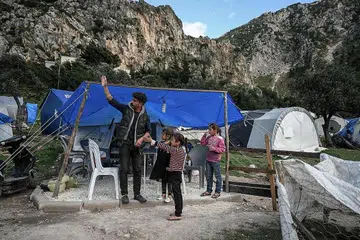 MENGHARAP BANTUAN: Encik Cuma Zobi, seorang pengawal keselamatan, melambai-lambai bersebelahan kanak-kanak di luar khemah sementara, dua bulan selepas gempa bumi menggegarkan Turkey. Unicef seru masyarakat antarabangsa menyalurkan bantuan tambahan. - Foto AFP