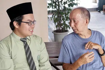 DEKATI MASYARAKAT: Encik Wong Chin Jiang (kanan), seorang guru pesara, amat terkesan dengan akhlak baik yang dipamerkan para pelajar MAI. Di kiri ialah pelajar MAI, Hasan Abdul Razak. Foto MADRASAH AL-ARABIAH AL-ISLAMIAH