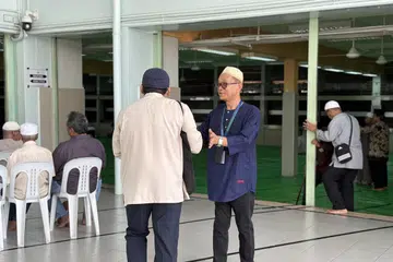 MENERIMA KEDATANGAN JEMAAH: Petugas dan sukarelawan masjid menerima kehadiran jemaah dan menunjukkan ruang solat sementara dan tempat wuduk untuk kemudahan jemaah yang hadir.