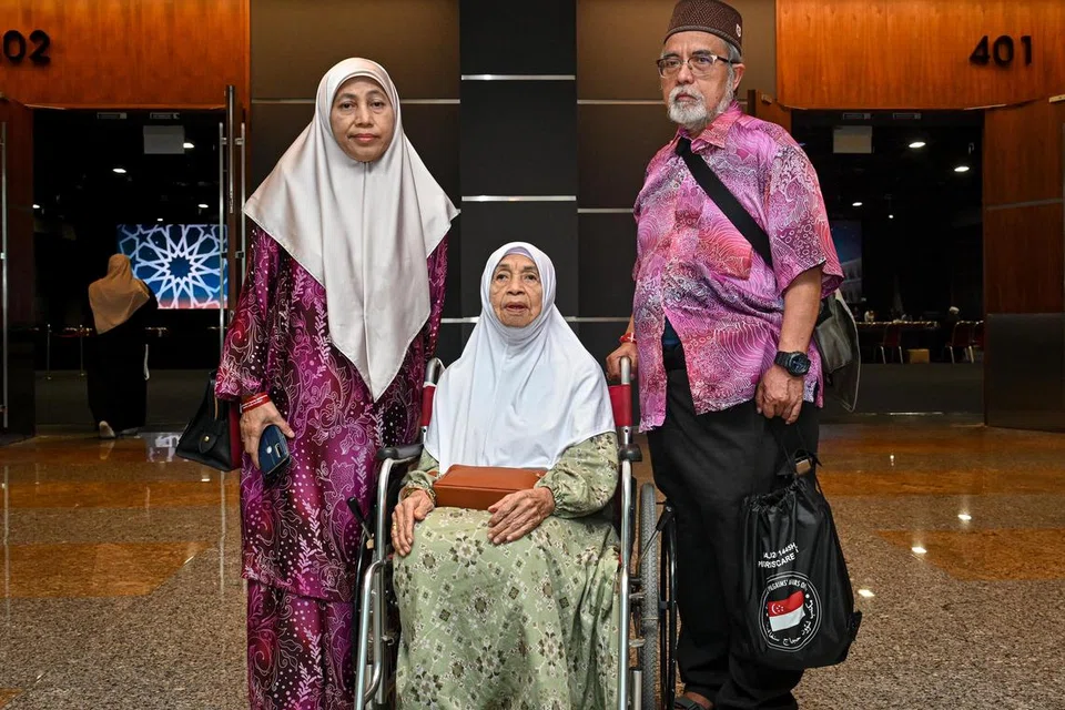 Cik Sapiah Mamat (tengah) adalah anggota jemaah haji yang tertua pada 2024. Beliau bakal menunaikan ibadah haji bersama anaknya, Cik Noraini Saliamin (kiri) dan menantunya, Encik Johari Saripan (kanan).