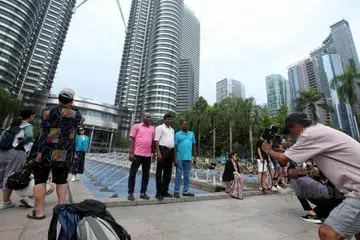 Pelancong asing bergambar di depan Menara Berkembar Petronas (KLCC) di Kuala Lumpur. Menurut jurugambar amatur di situ, mereka dari Sabah tetapi disebabkan mereka berkomunikasi dalam bahasa mereka sendiri, misalnya dialek Bajau, dan tidak menggunakan bahasa Melayu, timbul salah faham dan aduan bahawa mereka warga asing. 
