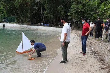 LEPASKAN JONG: Encik Desmond Lee (kemeja-T biru) melepaskan jong di lagun dengan disaksikan Encik Tan Chuan-Jin (kemeja-T merah) dan pengerusi FMP, Encik Mr Stephen Beng (kemeja-T putih). - Foto BH oleh TIMOTHY DAVID