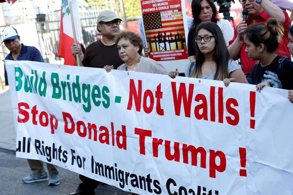 PROTES: Penunjuk perasaan di hadapan konsulat Mexico di Los Angeles, California, menayangkan sepanduk yang menunjukkan bangkangan mereka terhadap lawatan Encik Donald Trump ke Mexico. - Foto REUTERS