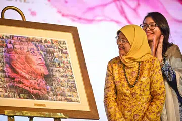 ‘MOZEK DETIK PERPADUAN’: Puan Halimah Yacob (kiri), yang diiringi Cik Hazlina Abdul Halim (kanan), menerima tanda penghargaan dalam bentuk kolaj yang memaparkan pelbagai usahanya mendekati dan memperjuangkan isu masyarakat. Karya yang dinamakan ‘Mozek Detik Perpaduan’ itu direka oleh Presiden 4PM, Encik Nassar Zain.