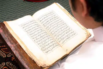 TARTIL: Seorang muslim sendang membaca Al Quran.