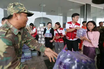 HULUR BANTUAN: Pasukan Palang Merah Singapura yang memakai jaket merah (dari kiri) Cik Jacqueline Ng, Cik Geraldine Aggarao dan Encik Samuel Lee membantu menyusun bekalan yang dibawa mereka termasuk air botol, mi segera, makanan dalam tin dan sebagainya. - Foto-foto BH oleh JONATHAN CHOO KK 