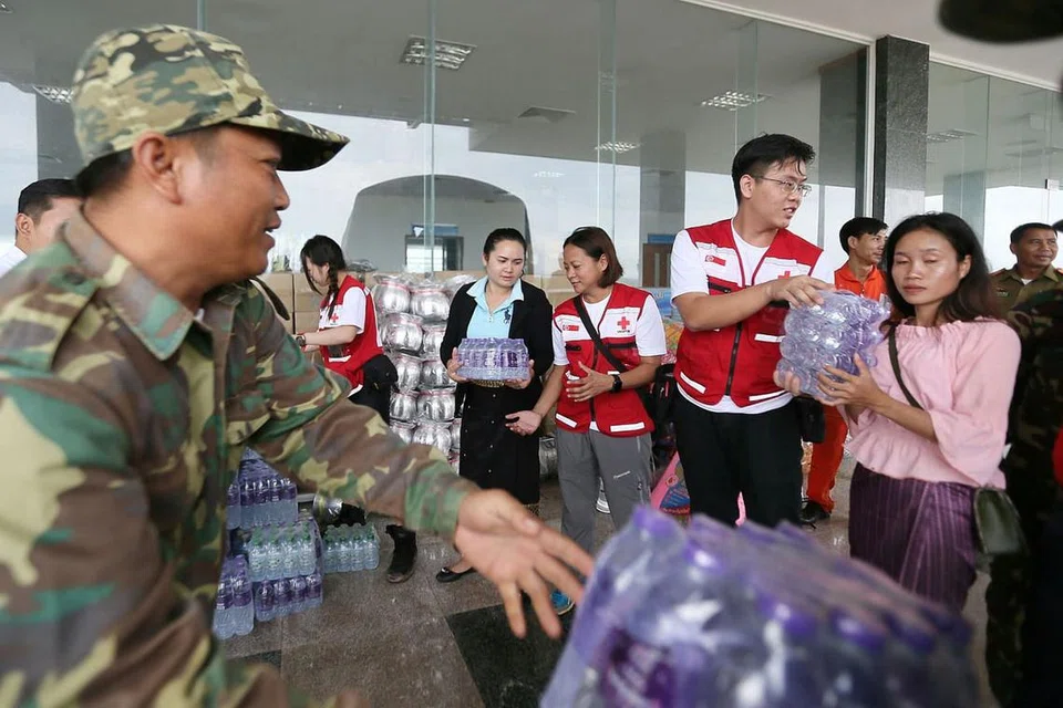 HULUR BANTUAN: Pasukan Palang Merah Singapura yang memakai jaket merah (dari kiri) Cik Jacqueline Ng, Cik Geraldine Aggarao dan Encik Samuel Lee membantu menyusun bekalan yang dibawa mereka termasuk air botol, mi segera, makanan dalam tin dan sebagainya. - Foto-foto BH oleh JONATHAN CHOO KK 