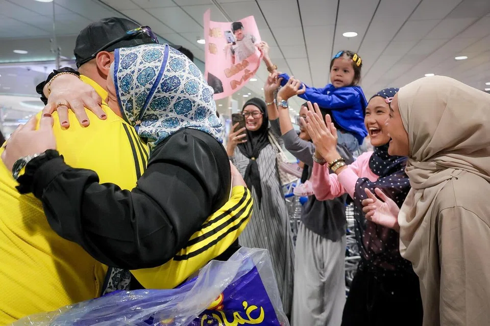 Cik Norislinda Mohamad Esah (dua dari kiri) memeluk suaminya, Encik Ricominoroy Purnama selepas beliau selamat pulang ke Singapura dari Abu Dhabi di Dewan Ketibaan Terminal 3 Lapangan Terbang Changi sekitar 9.20 malam pada 7 Mac.