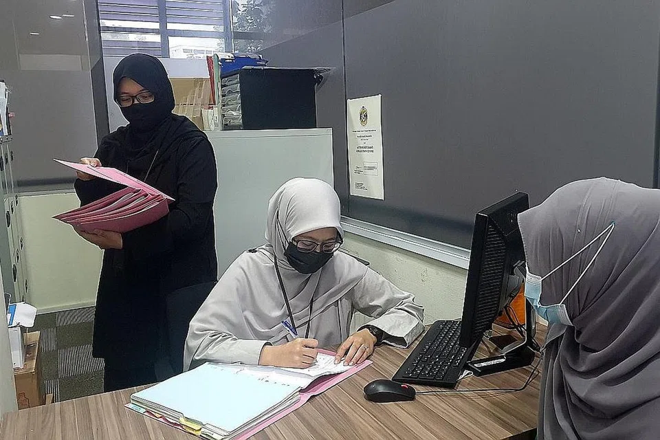 HULUR BANTUAN KEPADA GOLONGAN YANG MEMERLUKAN: Pegawai Pembangunan Sosial Masjid Darul Makmur, Ustazah Siti Mahjubah (berdiri) dan Ustazah Nur Insyirah (duduk, tengah), sedang memeriksa borang permohonan bantuan zakat untuk mereka yang hadir melalui sesi temu janji. - Foto MASJID DARUL MAKMUR