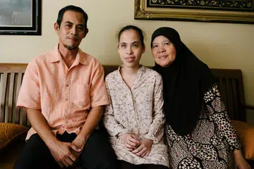 TERANG HATI: Walau mata kiri buta sepenuhnya dan mata kanan pula sekadar melihat cahaya dan bayangan, namun, Cik Siti Sakinah, bekas pelajar Politeknik Nanyang (NYP), tetap berjaya memperolehi Gred Purata Mata (GPA) 3.42 bagi Diploma dalam Pengurusan Perniagaan selain Gred 6 bagi piano. Belliau diapit ibu bapanya, Encik Zainal Osman dan Cik Rubiah Ghazali. - Foto BH oleh ALVIN HO