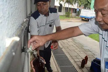 SIASAT PUNCA PERUBAHAN WARNA: Pegawai PUB mengambil sampel air daripada paip untuk disiasat di BMTC Pulau Tekong November lalu. - Foto fail