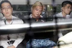 DISERET KE MAHKAMAH: Pemilik kedai telekomunikasi, Jover Chew (tengah), yang ditahan reman tiba di Mahkamah Negara pagi tadi dengan menaiki van polis. - Foto THE STRAITS TIMES