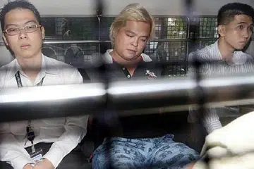 DISERET KE MAHKAMAH: Pemilik kedai telekomunikasi, Jover Chew (tengah), yang ditahan reman tiba di Mahkamah Negara pagi tadi dengan menaiki van polis. - Foto THE STRAITS TIMES