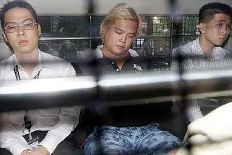DISERET KE MAHKAMAH: Pemilik kedai telekomunikasi, Jover Chew (tengah), yang ditahan reman tiba di Mahkamah Negara pagi tadi dengan menaiki van polis. - Foto THE STRAITS TIMES