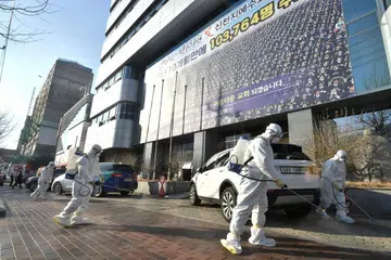 Beberapa pekerja melakukan pembasmian kuman di luar satu cawangan gereja Shincheonji Church of Jesus di Daegu, Korea Selatan pada 19 Februari 2020. Foto: AFP. 