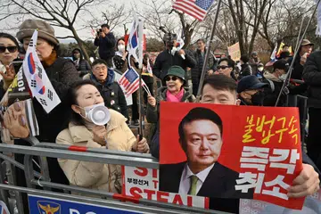 Penyokong Presiden Korea Selatan yang ditahan dan dipecat, Yoon Suk Yeol, berhimpun di luar Pusat Tahanan Seoul di Uiwang pada 7 Mac 2025 sambil memegang plakad merah yang memaparkan gambar Yoon dengan tulisan “Batalkan penahanan haram serta-merta!”. Pada hari yang sama, mahkamah Korea Selatan membatalkan waran tangkap terhadap Yoon.