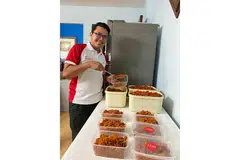 PERMINTAAN LAUK RAYA MELONJAK: Tukang masak utama Dapurnaes, Encik Muhammad Izzaki Nasir, menyediakan lauk-pauk yang ditempah pelanggan dari dapur flat di Punggol. - Foto DAPURNAES