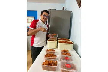 PERMINTAAN LAUK RAYA MELONJAK: Tukang masak utama Dapurnaes, Encik Muhammad Izzaki Nasir, menyediakan lauk-pauk yang ditempah pelanggan dari dapur flat di Punggol. - Foto DAPURNAES